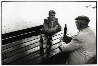 107967 Afbeelding van twee thuisloze mannen aan een picknic bank in het Wilhelminapark te Utrecht, met enkele flesjes bier.